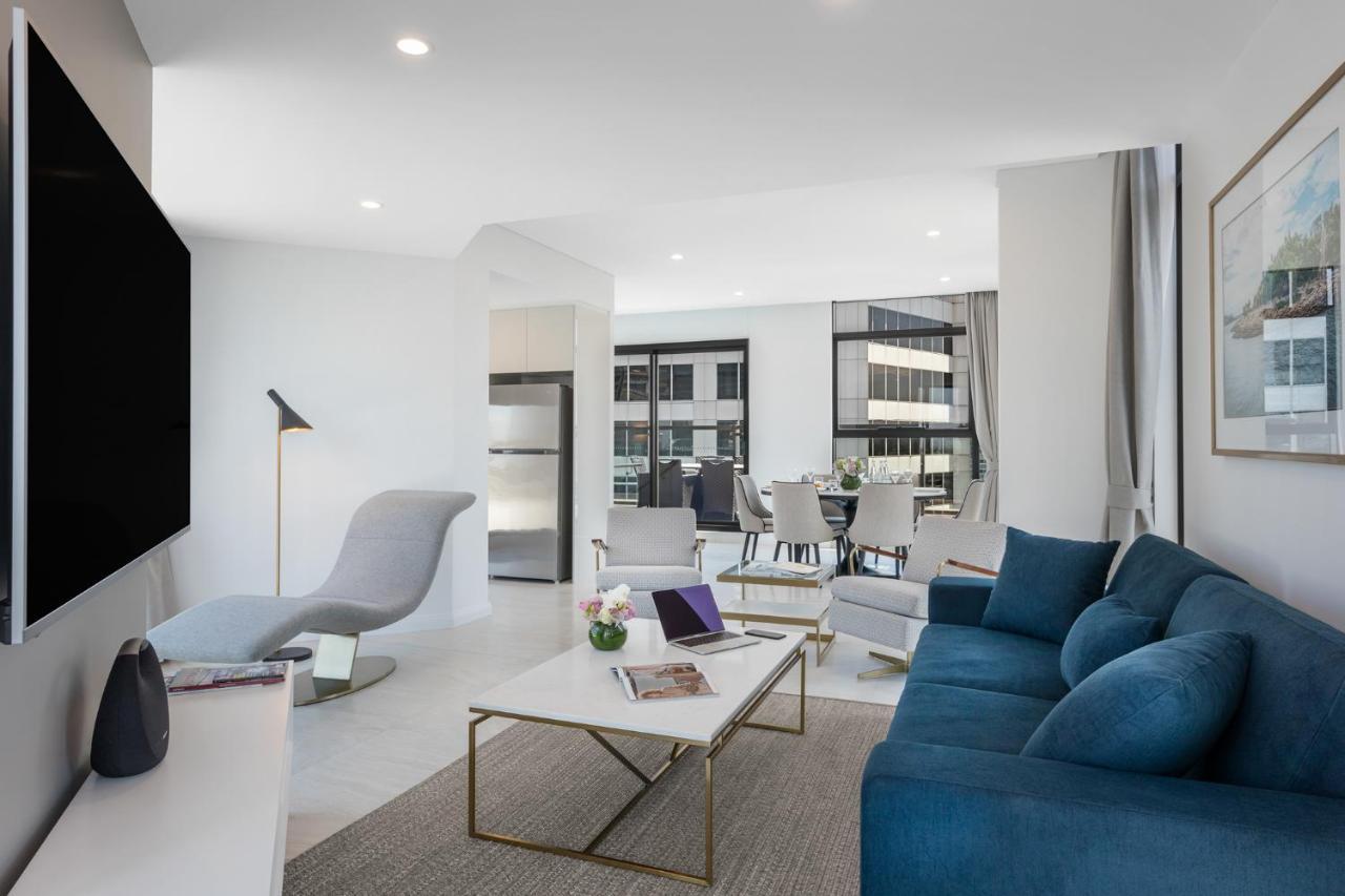 Meriton Suites Sussex Street, Sydney Kültér fotó The photo shows a modern living space that features a bright and stylish interior. Key elements include:

- A sleek blue sofa and a light gray lounge chair, providing comfortable seating.
- A coffee table with a minimalist design, positioned in front
